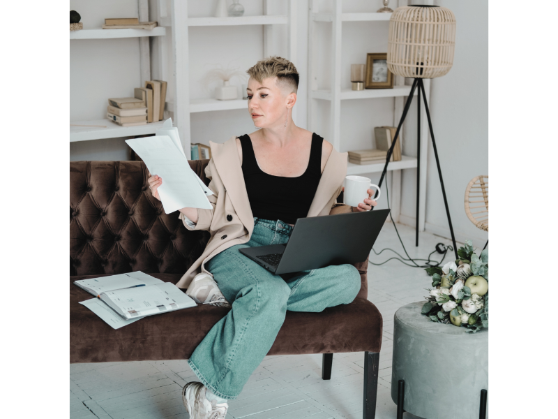 Woman sitting on a sofa working with laptop and papers